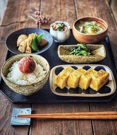 an assortment of sushi on a tray with chopsticks