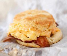 an egg and bacon biscuit sandwich is on wax paper