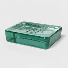 a green glass soap dish sitting on top of a white table