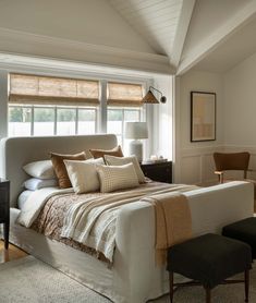 a large bed sitting under a window next to a desk and chair in a bedroom