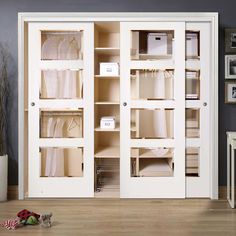 an open closet with white linens and other items on the floor next to it