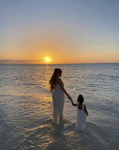 a woman and child in the water at sunset