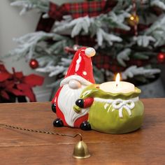 a candle holder with a santa clause on it sitting next to a christmas tree in the background