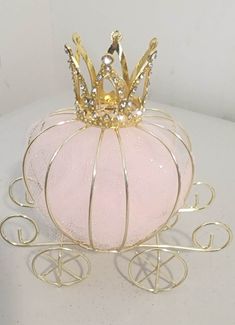 a pink glass pumpkin with a gold crown on it's head sitting in a carriage