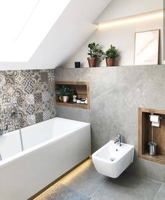 a white bath tub sitting next to a toilet in a bathroom under a skylight