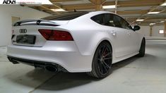 the rear end of a white car parked in a garage