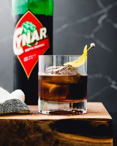 a close up of a drink on a wooden table with a bottle in the background