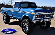 a blue truck parked in a parking lot next to a ford logo on the ground