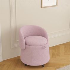 a pink chair sitting on top of a hard wood floor next to a white wall