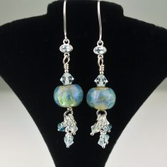 "This new pair of lampwork earrings features my handmade lampwork beads in a beautiful iridescent opalesque blue. I have embellished these beads with coordinating Swarovski crystals and sterling silver beads, then dangled them from sterling silver wire that has a light blue topaz setting. These one of a kind earrings measure 2.5\" from top to bottom, and will arrive beautifully packaged. To view more jewelry and handmade glass beads, click here: http://www.stonedesignsbysheila.etsy.com" Iridescent Light, Crystal Bead Jewelry, Lampwork Earring, Handmade Lampwork Bead, Handmade Glass Beads, Lampwork Glass Beads, Topaz Gemstone, Earrings Sterling Silver, Lampwork Beads