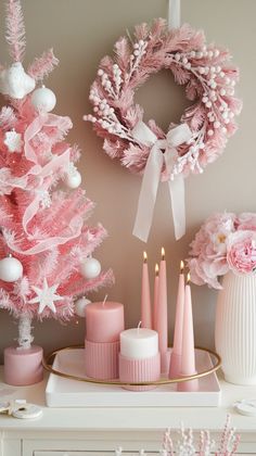 a pink christmas tree with candles and wreaths on the mantle in front of it