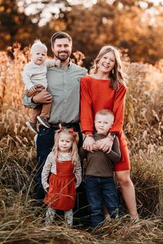 a family posing for a photo in the middle of a field with tall grass and trees