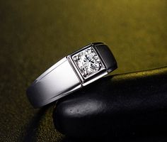 a diamond ring sitting on top of a piece of black stone next to a rock