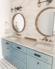 two bathroom sinks with mirrors above them in front of a tiled wall and white tiles on the floor