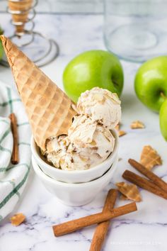 an ice cream sundae in a bowl with cinnamon sticks and green apples behind it