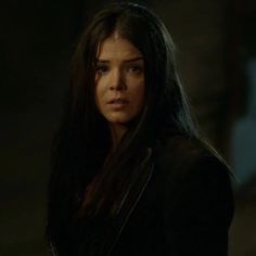 a woman with long dark hair standing in the dark