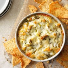 a bowl of cheese dip surrounded by tortilla chips