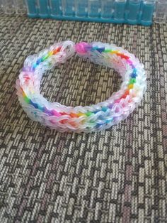 there is a small plastic container on the floor next to a rainbow - colored bracelet