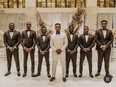 a group of men standing next to each other wearing suits and bow ties with their hands in their pockets