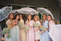 a group of women standing next to each other holding umbrellas and flowers in their hands