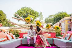 a man and woman sitting on top of a couch next to each other in front of flowers