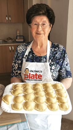 an older woman holding a tray of pastries