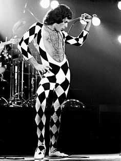 a woman in checkered pants standing next to a black and white photo with the caption