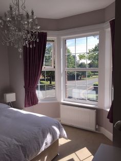 a bedroom with a chandelier hanging from the ceiling next to a large window