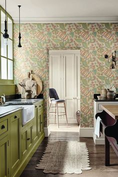 a kitchen with green cabinets and wallpaper on the walls is pictured in this image