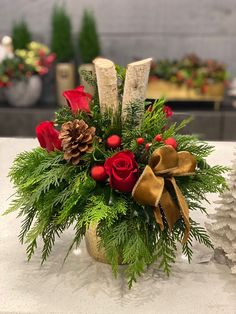 a christmas arrangement with red roses, pine cones and greenery