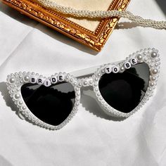 Elevate your event with our exquisite Custom Pearl Heart-shaped Sunglasses, meticulously handcrafted to add charm and glamour to your special day. PRODUCT DETAILS ❤❤ Each pair is adorned with luxurious pearls, sparkling rhinestones, and can be personalized with your chosen custom saying, perfectly tailored to complement your event's theme. ❤❤  Ideal for capturing cherished memories at Bridal Parties, Engagement Parties, Bachelorette celebrations, or romantic Honeymoons. SHIPPING & RETURNS ❤❤  Please note, due to the personalized nature of our sunglasses, exchanges are not available for items featuring custom last names. In case of shipping damage, simply photograph the issue and reach out to us for a prompt resolution. Celebrate in unparalleled style with these glamorous sunglasses, design Groom Sunglasses, Bridal Glasses, Sunglasses Bride, Sunglasses Bachelorette, Bridal Sunglasses, Hen Do Party, Bridesmaid Glasses, Bachelorette Sunglasses, Pearl Sunglasses