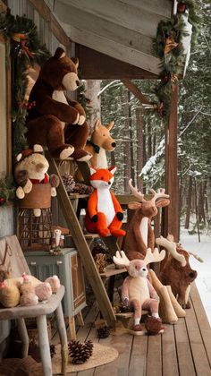 stuffed animals are lined up on the porch in front of a christmas tree and ladder