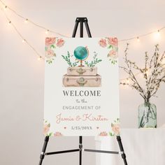 a welcome sign on a easel in front of a string of lights and flowers