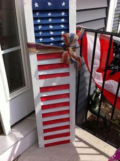 an american flag made out of old shutters on the side of a house with red, white and blue decorations