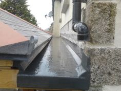 the gutter is attached to the side of the house and has water running down it