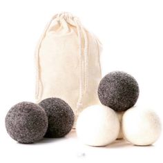 three balls of wool sit in front of a drawstring bag on a white background