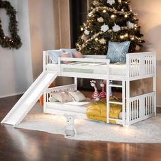 a white bunk bed with a slide next to a christmas tree