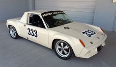 a white race car parked in front of a garage door with numbers on the side