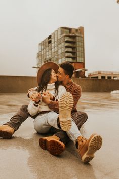 a man and woman sitting on the ground kissing