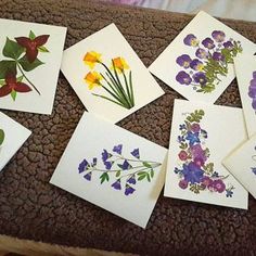 several cards with flowers on them sitting on a table