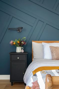 a bedroom with blue walls and white bedding has a wooden headboard on the nightstand