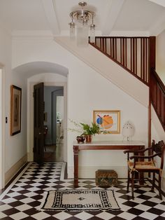 a hallway with black and white checkered flooring next to a wooden banister