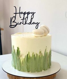 a green and white cake sitting on top of a wooden table with a happy birthday sign