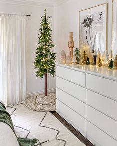 a living room with a christmas tree in the corner and other decorations on the dresser