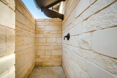 an empty corner of a building with no doors on the outside and light tan brick walls