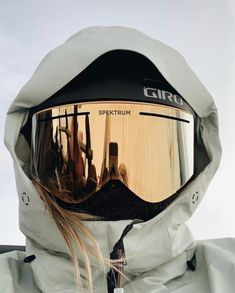 a person wearing ski goggles and a white jacket with the reflection of buildings in it