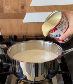 a person is pouring milk into a pot on the stove