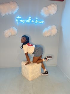 a woman is sitting on top of a stool with clouds above her and the words, it's all a dream