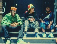 three people sitting on the steps wearing hats