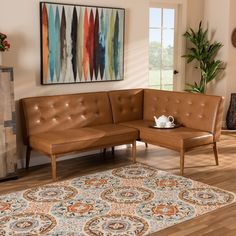 a brown leather couch sitting on top of a wooden floor next to a rug and potted plant